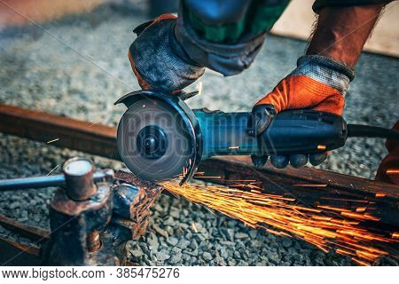 A Man Is Sawing Metal With An Angle Grinder.