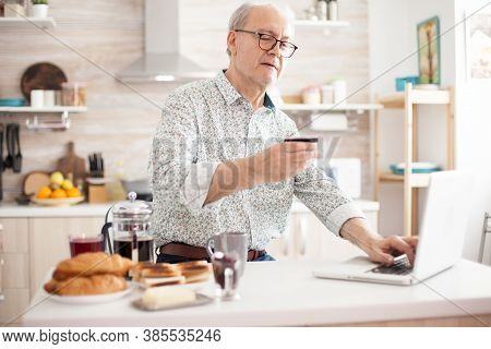 Retired Man Entering Pin Number While Shopping Online On The Internet. Pensioner Paying Online Using