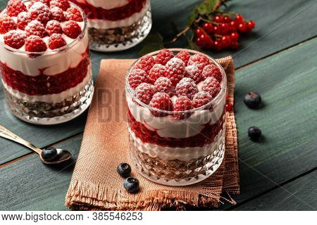 Healthy Raspberry Fruit Dessert With Skyr Yogurt, Granola Layered In Jar Surrounded By Ingredients, 