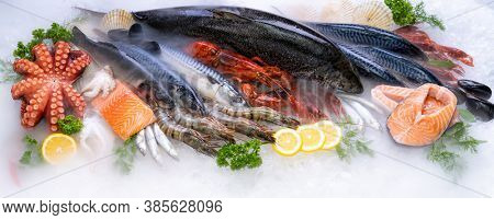 Panoramic web banner crop Top view of variety of fresh luxury seafood, Lobster salmon mackerel crayfish prawn octopus mussel and scallop, on ice background with icy smoke in seafood market. 