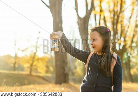 Hourglass And Autumn Dry Leaves. Withering Time Is Autumn.