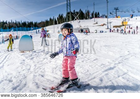 Young Happy Skier Girl Learning How To Ski On The Green Ski Zone. Young Skier Having Fun On Ski Slop