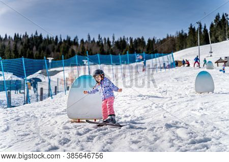 Young Happy Skier Girl Learning How To Ski On The Green Ski Zone. Young Skier Having Fun On Ski Slop
