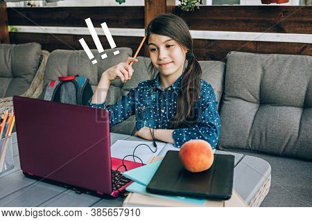 Smiling Little Schoolgirl Doing Her Homework In Front Of A Laptop. Distance Learning.