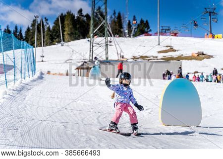 Young Happy Skier Girl Learning How To Ski On The Green Ski Zone. Young Skier Having Fun On Ski Slop