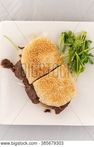 Appetizing Plate Tempting The Tastebuds With Beef Sandwich In Sesame Bun In Perfect Serving Size.