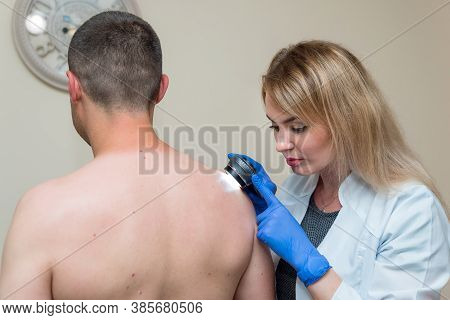 The Doctor Examines The Patient's Skin With An Optical Device