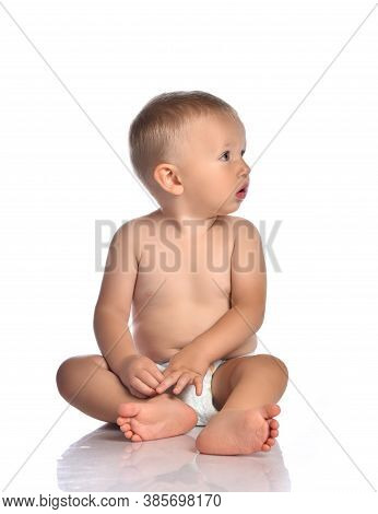 Calm Blond Baby Boy Toddler Naked In Diaper Sits On The Floor With Head Turned And Looks Aside Over 
