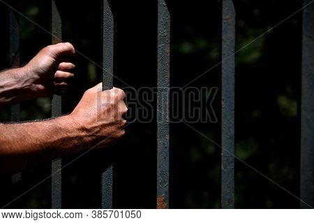 Two Hand Holding Steel Bars At A Fence