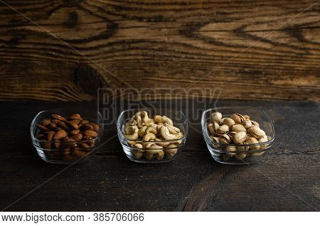 Almond, Cachew And Walnut In A Small Plates Which Standing On A Black Table. Nuts Is A Healthy Veget