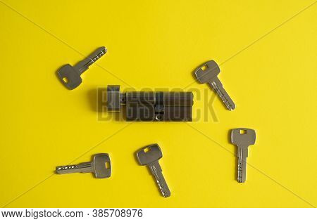 A Door Lock Cylinder Core With Keys On The Yellow Background. The Cylinder Of The Lock With Keys. In