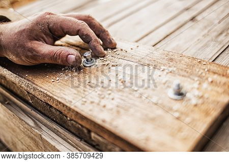 Male Hands Screw A Bolt Into A Wooden Board. Close-up, Selective Focus