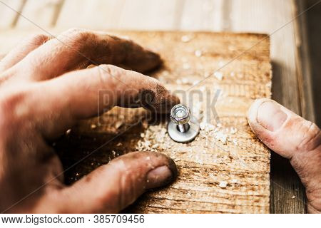 Male Hands Screw A Bolt Into A Wooden Board. Close-up, Selective Focus