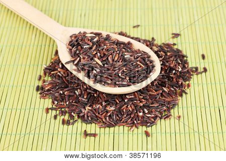 arroz preto com colher de pau, na esteira de bambu