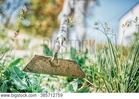 Young Girl Cultivates The Earth With A Hoe. Hoe Close-up, Selective Focus.