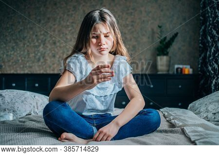 Young Brunette Girl Is Sitting On The Bed In Her Room, Her Finger Hurts.