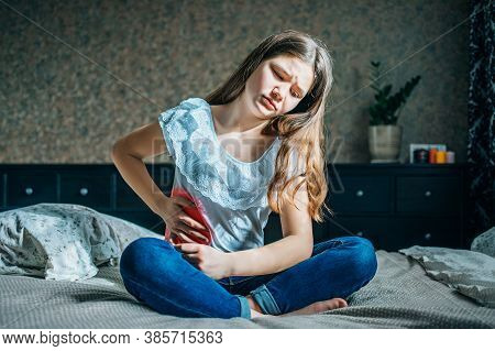Young Brunette Sits On A Bed In Her Room, Holds A Sick Stomach With Her Hand, Horizontal Shot, Selec