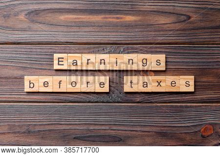 Earnings Before Taxes Word Written On Wood Block. Abbreviation Ebt Text On Cement Table For Your Des