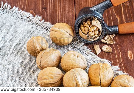 Close-up Of A Walnut And Nutcracker. Freshly Cracked Walnut In A Nutcracker On A Wooden Background A