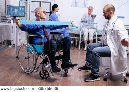 Senior Man In Wheelchair Exercising Muscle Strength. Invalid Physiotherapy Program, Health Care Inju