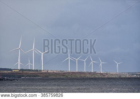 Wind Wheels In The Sea On Blue Sky Background. Wind Energy.