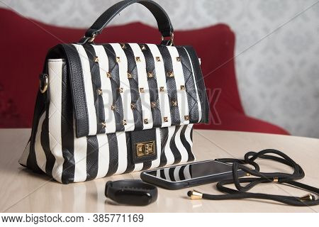 Sunglasses, earrings and striped bag on the table in the room, elegant life style concept