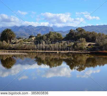Dunes With Vegetation Reflected In The Water, Mountains And Blue Sky, Maspalomas, Gran Canaria