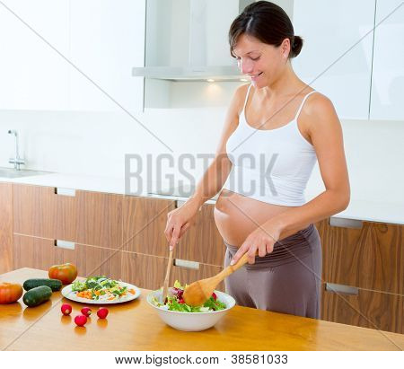 Bella donna incinta a casa cucina preparazione insalata