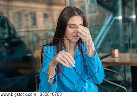 Woman With Glasses Suffering From Eyestrain, Pain In Eyes Or Nose From Specs Sitting At Table At Her