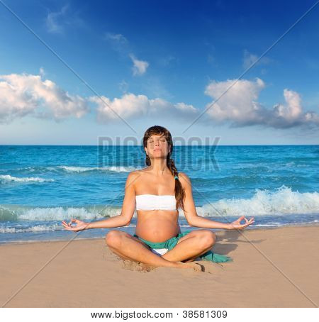 Bella donna incinta praticando lo yoga in spiaggia blu sabbia su vacanze estive