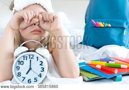 Back To School. Alarm,clock. Little Girl, Schoolgirl Sleeps In Bed,wakes Up Early To Study,rubs Eyes