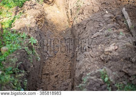 A Ditch Dug By An Excavator In The Ground For Laying A Water Supply System. Residential Water Supply