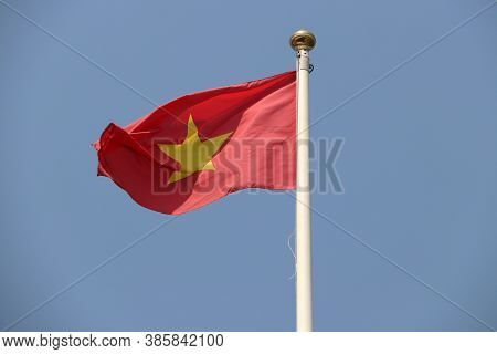 National Flag Of Vietnam On Bright Blue Sky Background. Blown Away By Wind. Vietnam Is One Of The Te