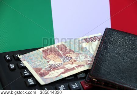 One Thousand Lire Of Italy Banknote With Black Wallet On The Calculator With Italia Flag Background,