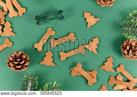 Top View Of Homemade Baked Dog Treat Cookies In Shape Of Bones And Christmas Tree On Festive Green B
