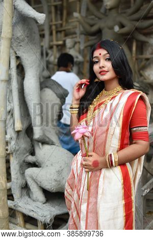 Portrait Of A Young And Beautiful Indian Woman In Red And White Traditional Ethnic Sari And Gold Jew