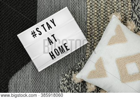 Pillow And Lightbox With Hashtag Stay At Home On Warm Knitted Blanket, Flat Lay. Message To Promote 
