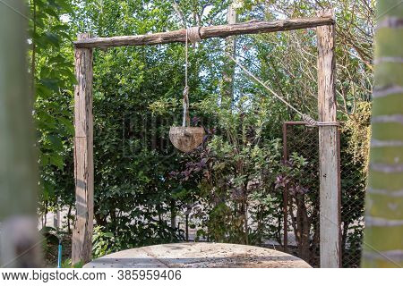Old Wooden Well (water Source) In Traditional Village Folk Style. At Time Of Scooping The Rope, Put 