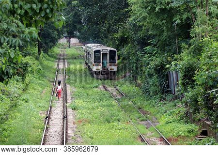 Behind Of Myanmarese Lady Villager Walking On The Railroad Tracks And Put The Black Bag Or Belonging