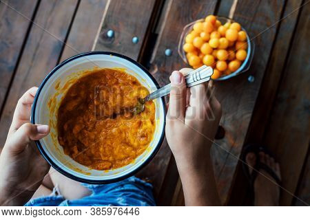 The Girl Prepares Jam From Yellow Plums. She Will Grind The Plums With A Fork.