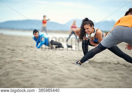 Young people doing stratching exercises on the beach on a beautiful weather