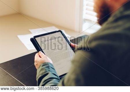 Close Up Man Reading Elecronic Rental Agreement On Tablet.