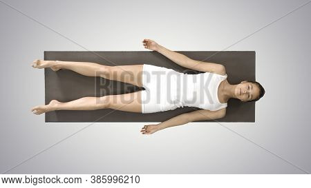Yoga Meditation Laying On A Mat With Closed Eyes On Gradient Bac