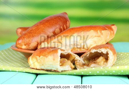Empanadillas al horno frescos con mermelada de frutas, en placa, en la mesa de madera, sobre fondo brillante