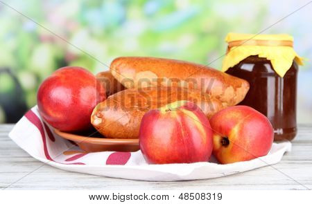 Empanadillas al horno frescos con mermelada de frutas, en la mesa de madera, sobre fondo brillante