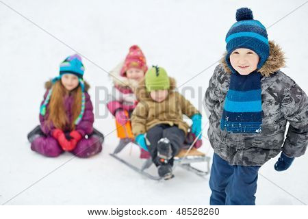 Jongen trekt slee met twee jongere kinderen, focus op jongen
