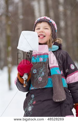 Meisje eet eskimo gemaakt van stuk van sneeuw en gebroken tak in winter park