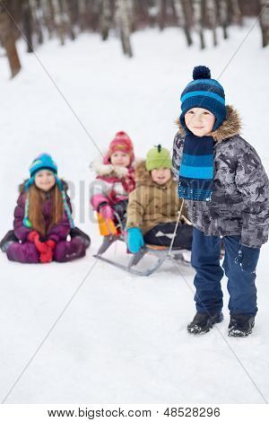 Jongen trekt slee met jongere kinderen in winter park, focus op jongen