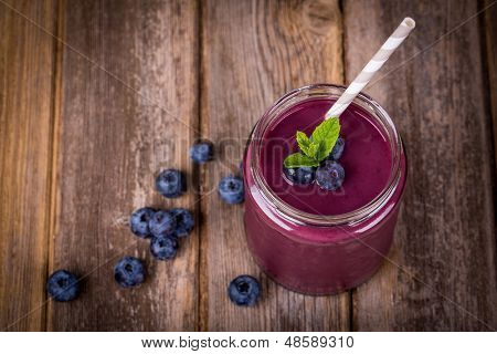 Borůvka smoothie zavařovačky s slámy a snítkou máty, vintage dřevěný stůl s čerstvým