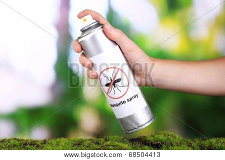 Hand holding mosquito spray on nature background